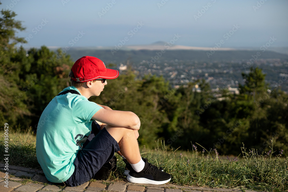 teenage boy walking on the mountain in the city in summer teenage boy walking on the mountain in the city in summer
