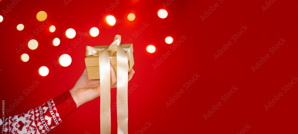 Girl hands holding christmas gift on red background. Christmas banner. Minimalism. Copyspace.