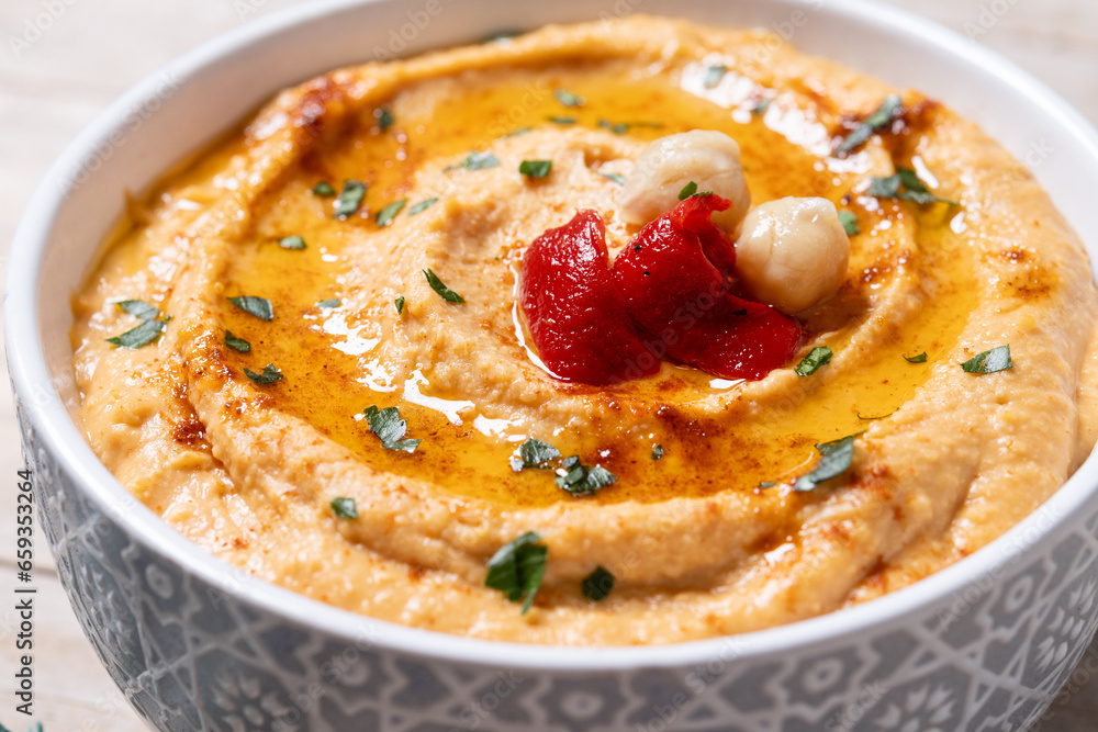 Roasted red pepper hummus in white bowl on wooden table