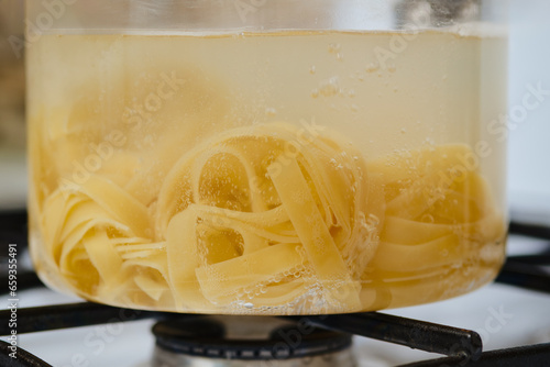 Closeup view of fettuccine pasta into boiling water in a saucepan photo