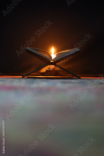 Quran in the mosque at night and light from the candle,The Quran in the Mosque - open for prayers, prayers of Muslims around the world, placed on a wooden board. 
