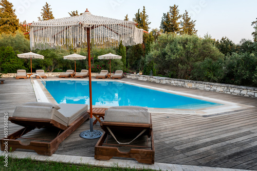 Swimming pool and beds for relaxing in summer. Swimming pool in the nature among greenery.