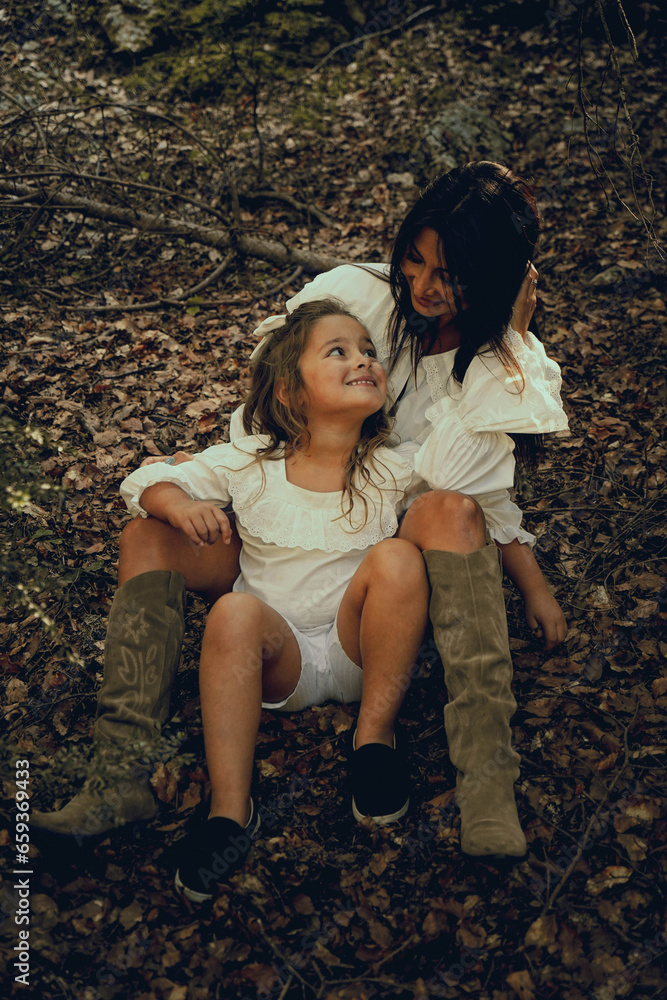 moment of complicity between a mother and her daughter sitting in nature. Autumn season moment of complicity between a mother and her daughter sitting in nature. Autumn season