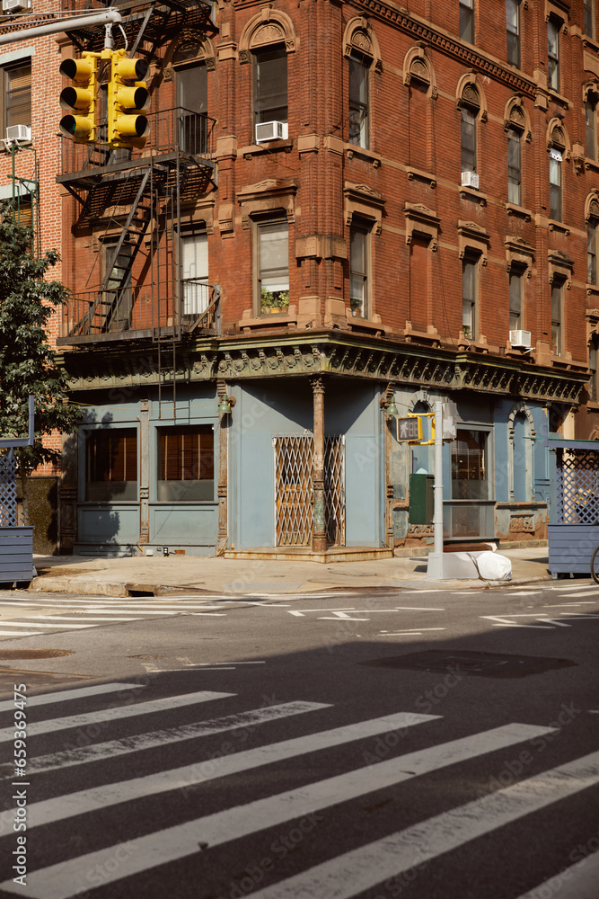 Obraz premium vintage building with fire escape stairs near pedestrian crossing in new york city, urban scene