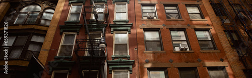 low angle view of vintage red brick house with fire escape stairs in new york city, banner