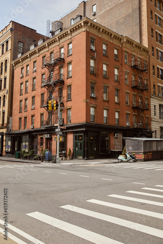 red brick building with storefront and fire escape stairs on crossroad in new york city, streetscape