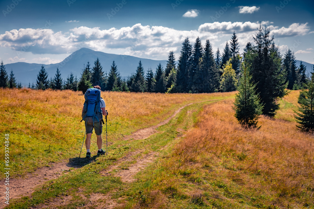 Trekking on the mountain road with Hoverla peak on background. Marvelous summer view of Carpathian Mountains, Ukraine, Europe. Active tourism concept background..