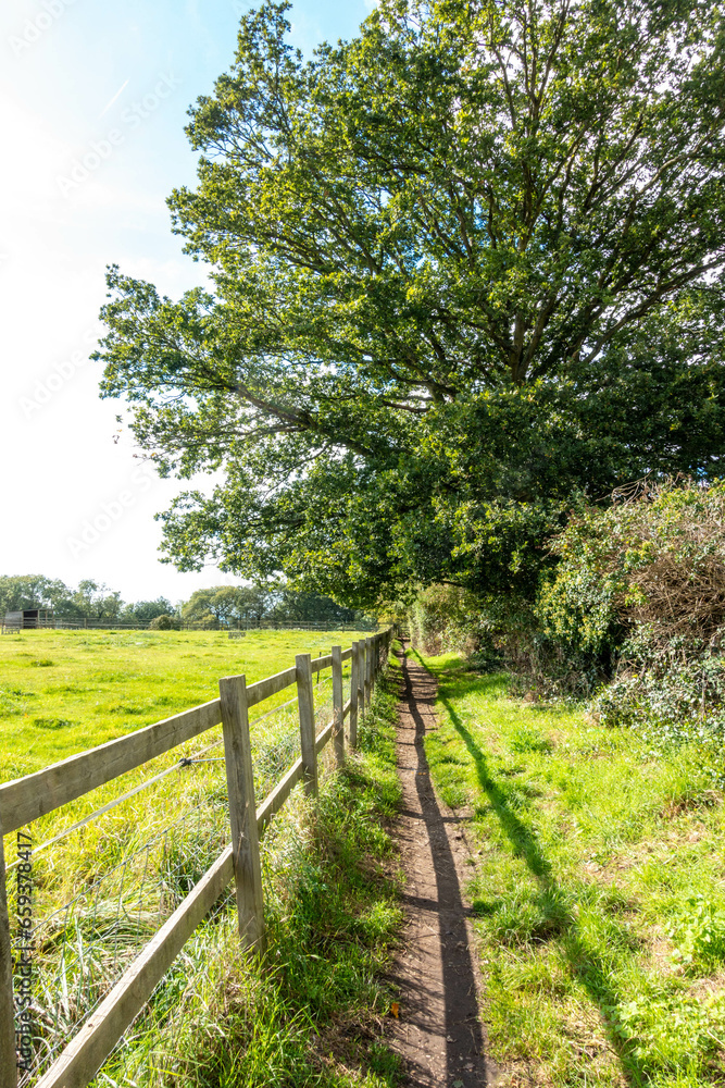 Walking down a countryside path past a field fenced off with a wooden fence