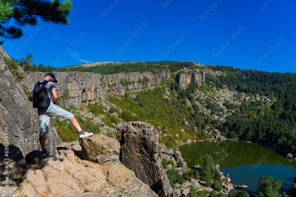 Man on top of a mountain with a lake in the background