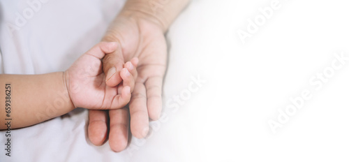 Hands of the woman and a child's hand on the white bed