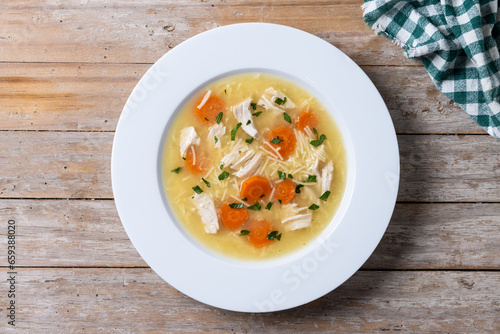 Chicken soup with vegetables on wooden table