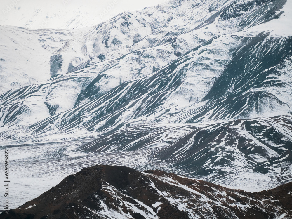 Scenic minimalist landscape with sunlit snowy mountain wall. Texture of snow-capped mountains. Minimalist nature background of snowy mountainside.