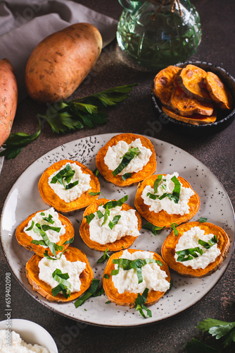 Baked sweet potato circles with cream cheese and parsley on a plate on the table vertical view