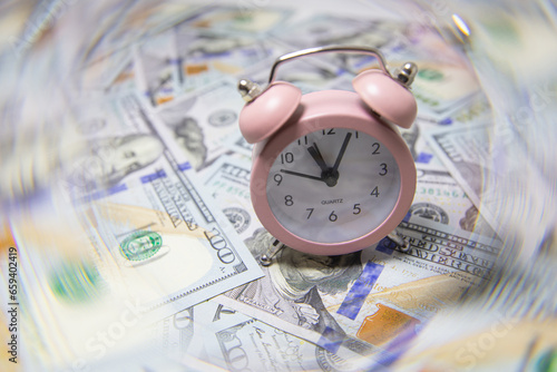 pink quartz alarm clock isolated on US 100 dollar banknotes