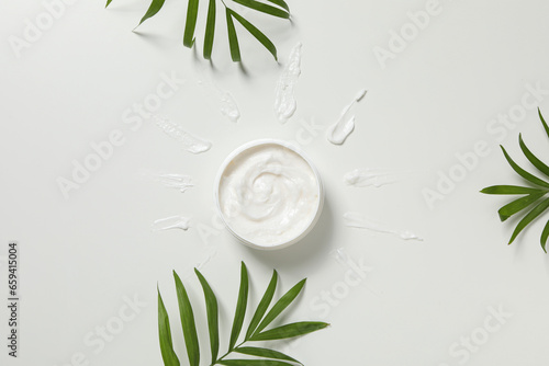 Jar with cream and leaves on white background, top view