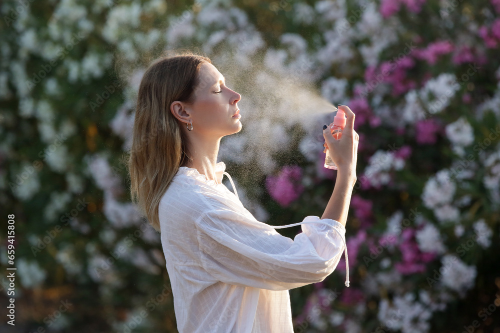 Woman spraying facial mist on her face, summertime skincare concept Woman spraying facial mist on her face, summertime skincare concept