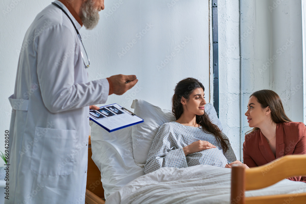 Obraz premium loving lgbt couple looking at each other at appointment with doctor holding ultrasound, ivf concept