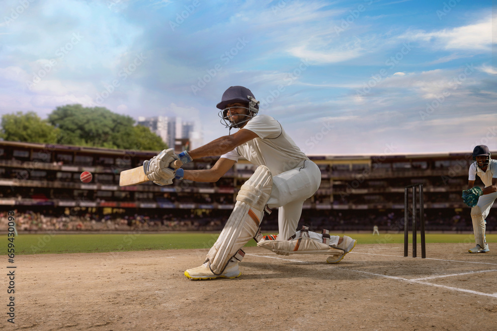 Cricketer batsman hitting a sweep shot during a cricket match on the pitch Cricketer batsman hitting a sweep shot during a cricket match on the pitch