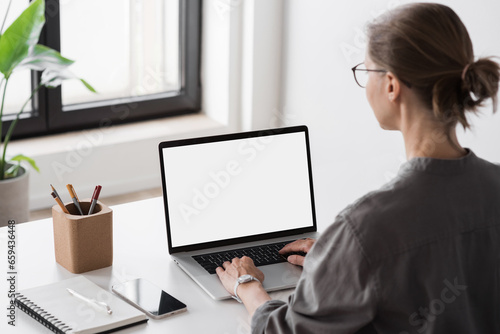 Young woman working at office, Student girl using laptop computer with blank empty screen, work or studying from home, freelance, online learning, distance education concept photo
