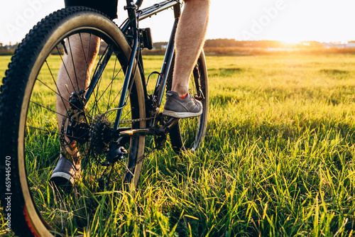 Close up of bicycle wheel off road at sunset time. low angle view of cyclist riding mountain bike. Healthy lifestyle and outdoor adventure concept