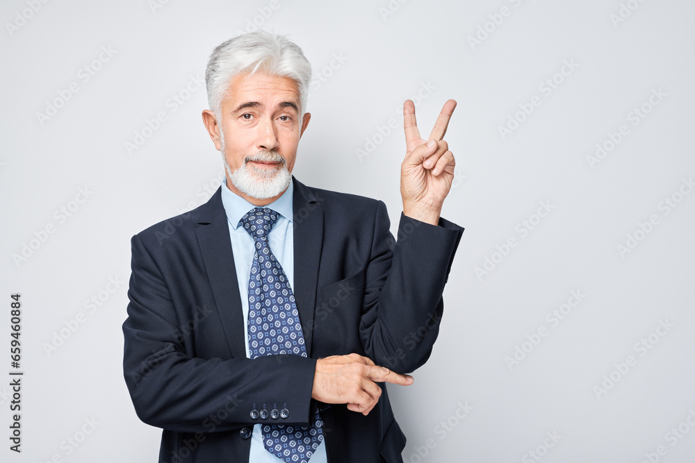 Portrait of positive adult businessman in suit showing peace and love gesture with fingers isolated on white studio background. Selfie pose, hello my friend concept. Portrait of positive adult businessman in suit showing peace and love gesture with fingers isolated on white studio background. Selfie pose, hello my friend concept.