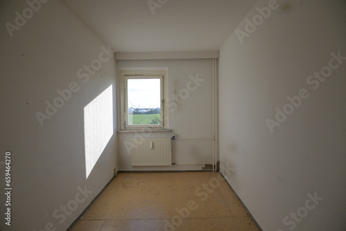 Narrow unrenovated room with heater and window, concept for housing shortage and small space living copy space photo