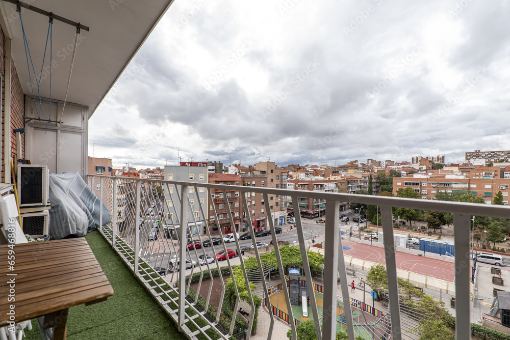 a terrace with artificial grass floor with white railing, clothesline on the ceiling, wooden table and folding chairs a terrace with artificial grass floor with white railing, clothesline on the ceiling, wooden table and folding chairs