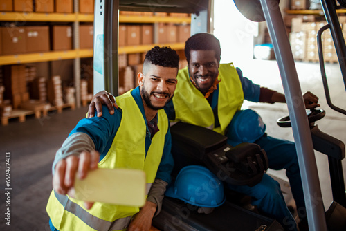 Two African American workers taking selfies in a warehouse