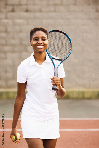 Portrait of a young beautiful women with tennis clothes and racket in a tennis court ready to play a game. © Jordi Salas
