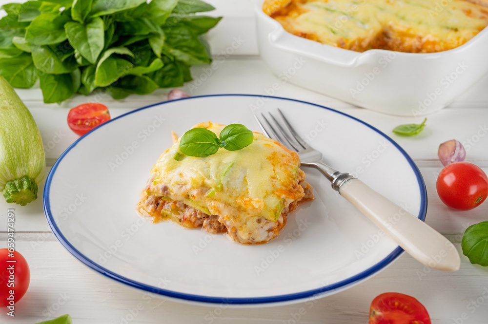 Delicious zucchini lasagna with sauce bolognese on a plate on a white wooden bachground. Healthy food. Top view. Selective focus. Delicious zucchini lasagna with sauce bolognese on a plate on a white wooden bachground. Healthy food. Top view. Selective focus.