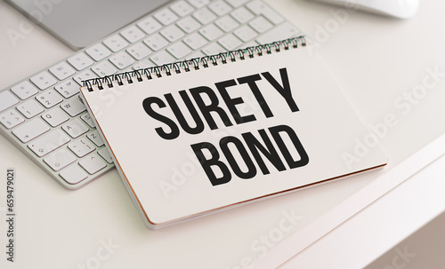 SURETY BOND text on a notebook with clipboard on white background