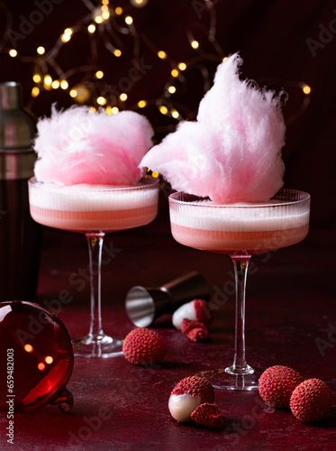 Lychee cocktail decorated with pink cotton candy. Christmas lights on the background
