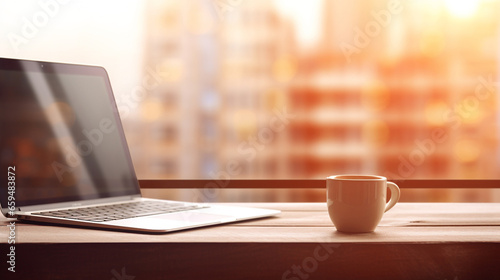 A laptop and a cup of coffee on the office table with a blurred background
