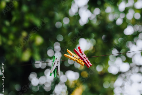 Colored plastic clothespins hanging on a rope outdoors. Close-up photography, housework.