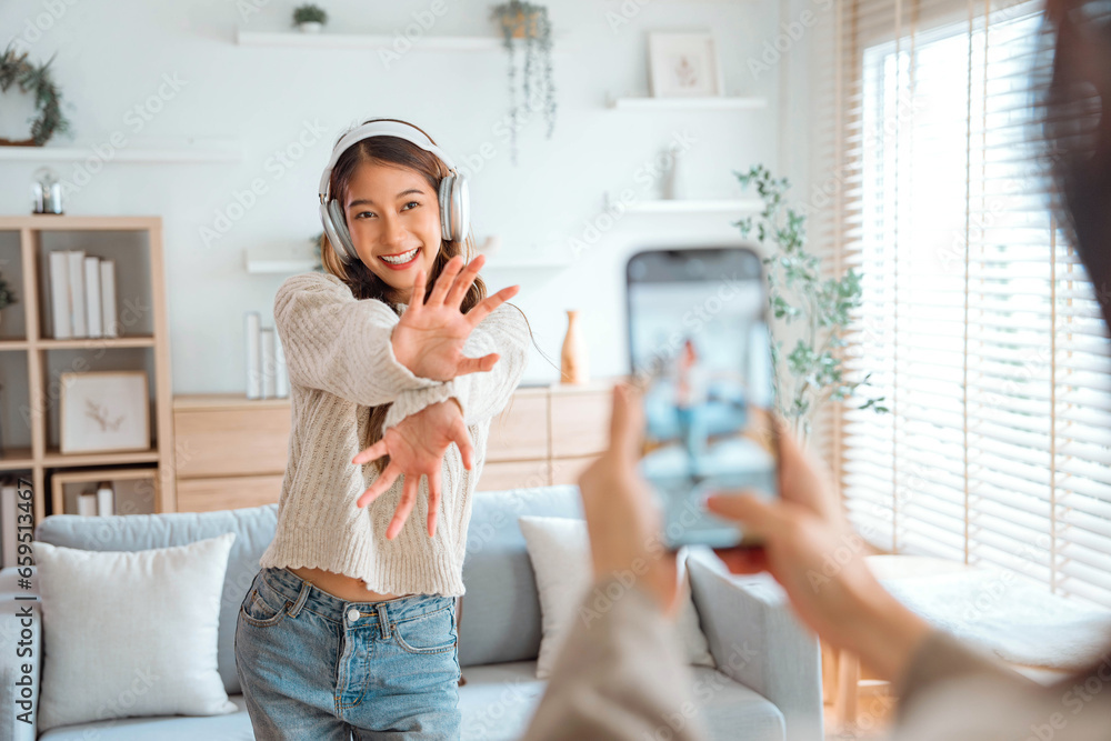 Happy young asian vlogger influencer woman with her friend cover dancing video by smartphone camera together, To share video on social media - obrazy, fototapety, plakaty 
