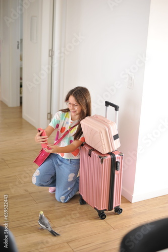 pré adolescente com celular fazendo foto com malas de viagem antes de sair de casa  photo