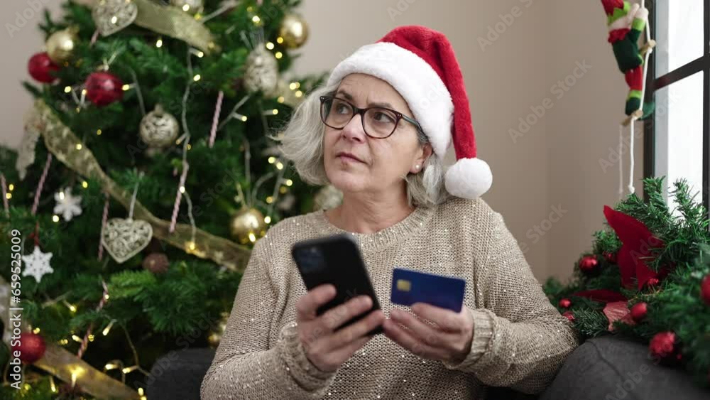 Middle age woman with grey hair doing christmas online shopping with smartphone at home Middle age woman with grey hair doing christmas online shopping with smartphone at home