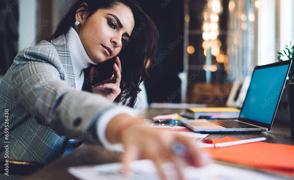 Serous female calling on smartphone taking document at workplace Serous female calling on smartphone taking document at workplace