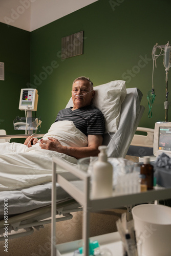 Senior man resting in a hospital, with an oxygen tube and finger oxygen monitor