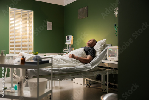 Person at hospital, asleep, using a breathing tube and a finger thing