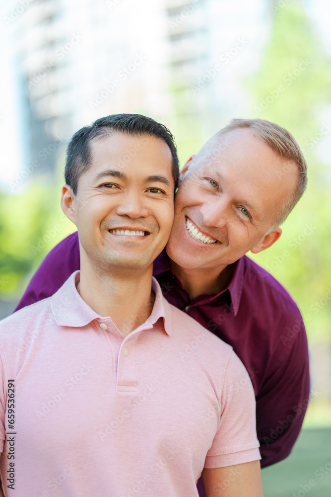 Portrait of smiling middle aged homosexual men hugging looking at camera on urban street Portrait of smiling middle aged homosexual men hugging looking at camera on urban street