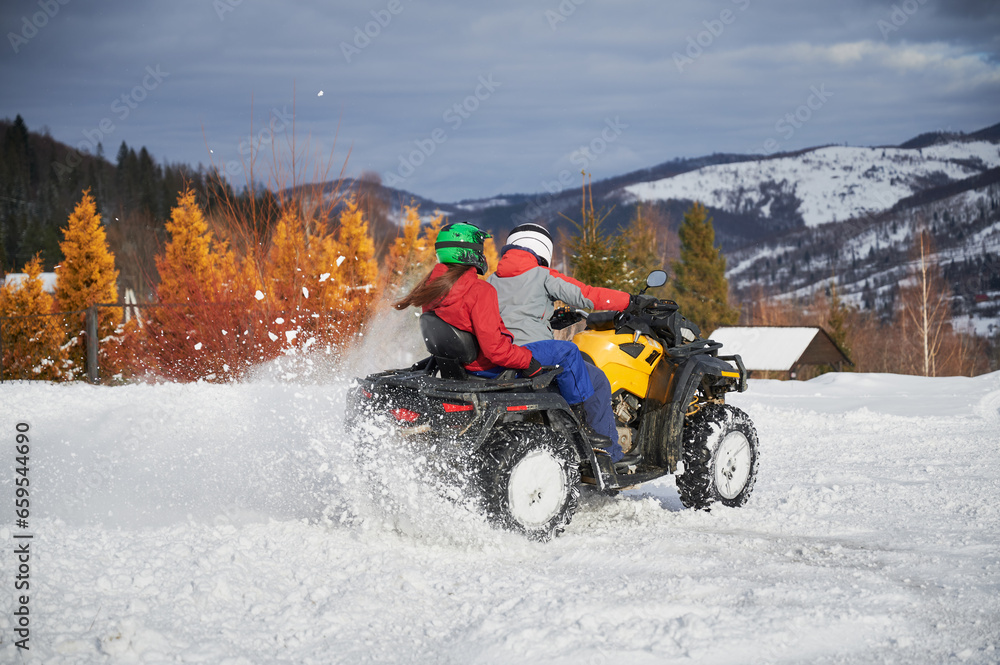 Portrait of man and woman riding on offroad four-wheeler ATV. Concept of active leisure and winter activities. Portrait of man and woman riding on offroad four-wheeler ATV. Concept of active leisure and winter activities.