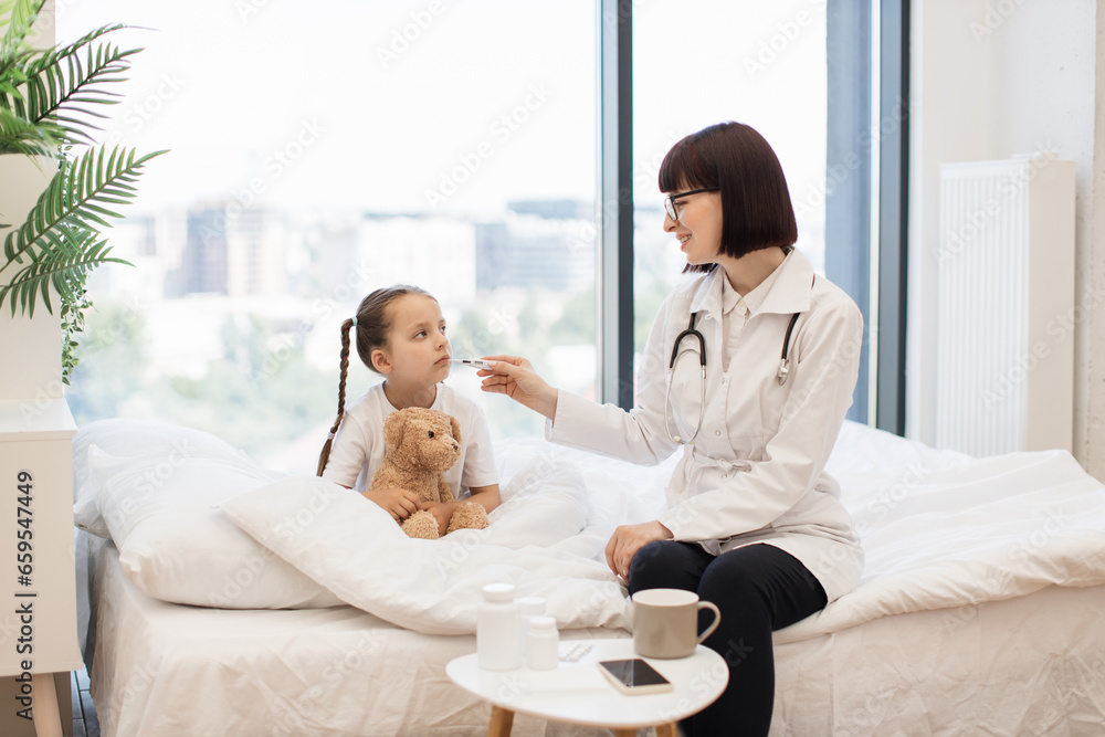 Sick little girl resting on comfy bed while diligent doctor conducting detailed health assessment. Caucasian pediatrician using electronic thermometer for checking child temperature. Sick little girl resting on comfy bed while diligent doctor conducting detailed health assessment. Caucasian pediatrician using electronic thermometer for checking child temperature.