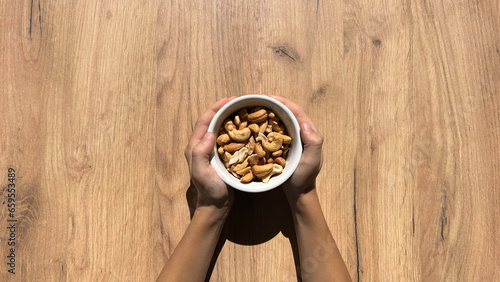 cashewsin in children's hands on a wooden background