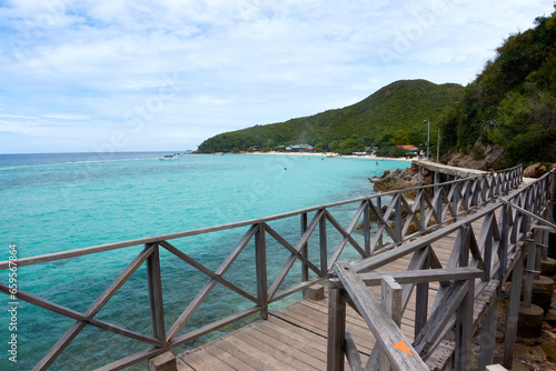 Seascape with a long wooden bridge and clear blue waters.