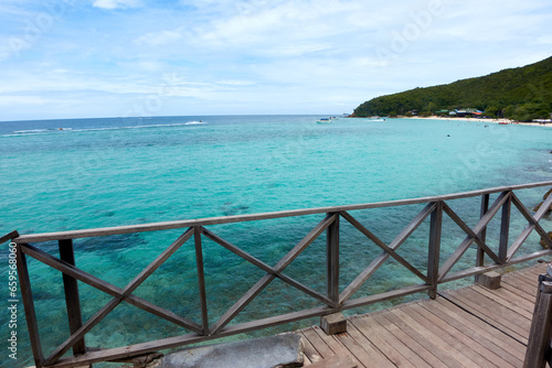 Seascape with a long wooden bridge and clear blue waters. © Kittipong