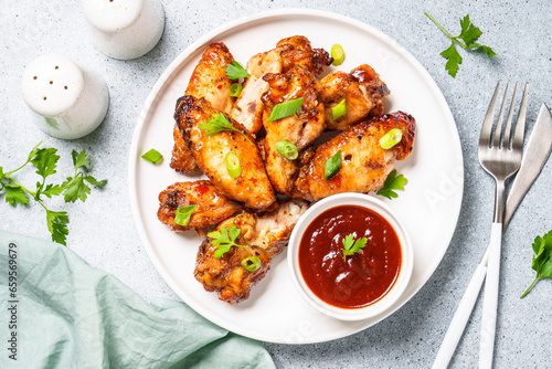 Grilled Chicken wings with sauce in craft plate at white table.