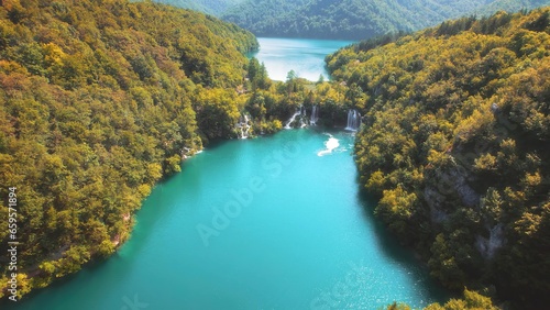 Scenic nature of waterfall with emerald pool of fresh water lake in summer green forest. Landscape of reservoir in national park.