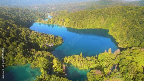 Green Mountain coniferous forest with deep blue lake. Dense wood landscape in summer to early autumn sunny morning. Clear fresh azure water.