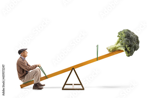 Full length profile shot of an elderly man and a broccoli on a seesaw photo